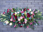 rouwbloemstuk in roze/rode tinten